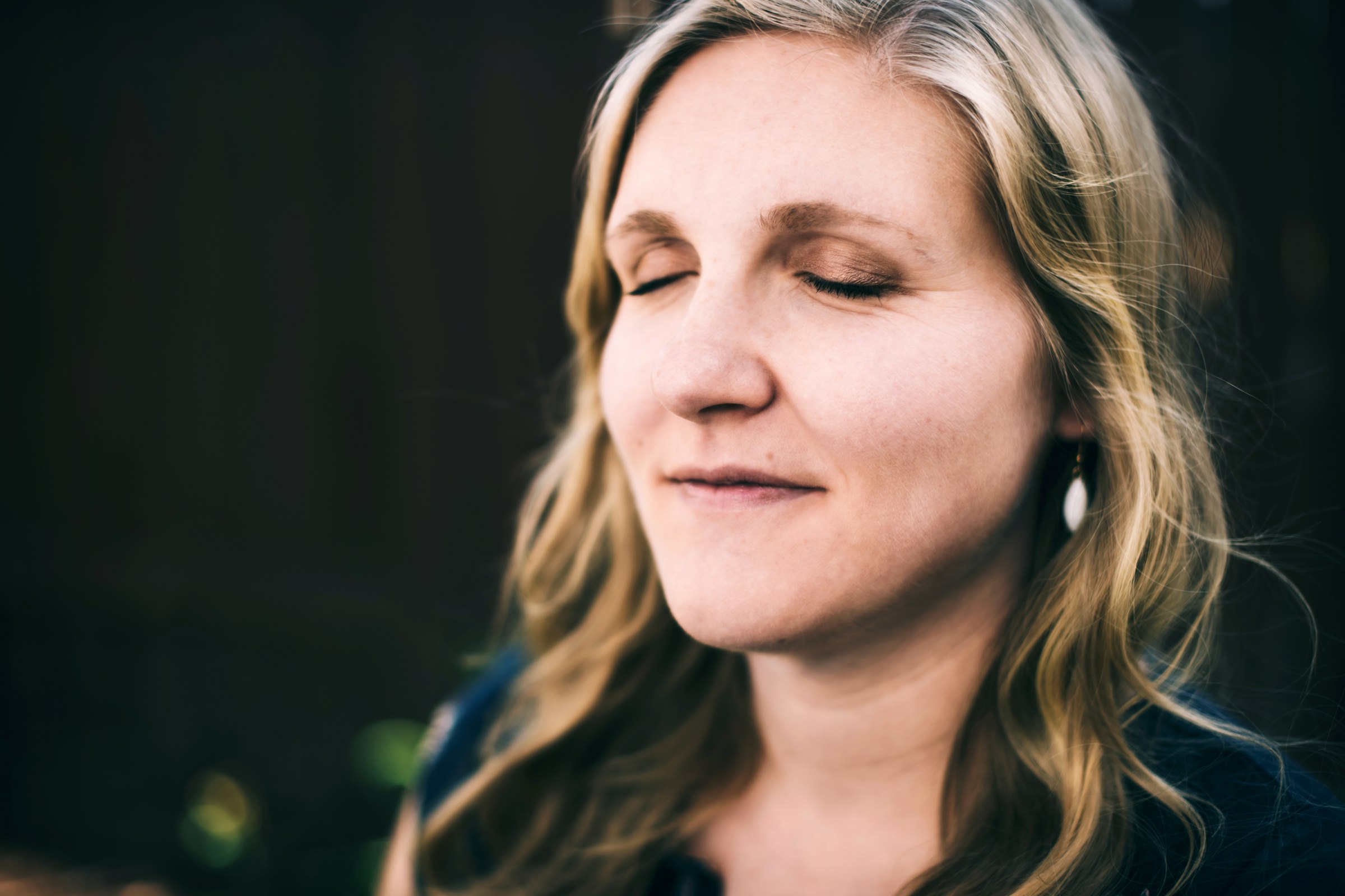 Woman in her forties with eyes closed in soft light